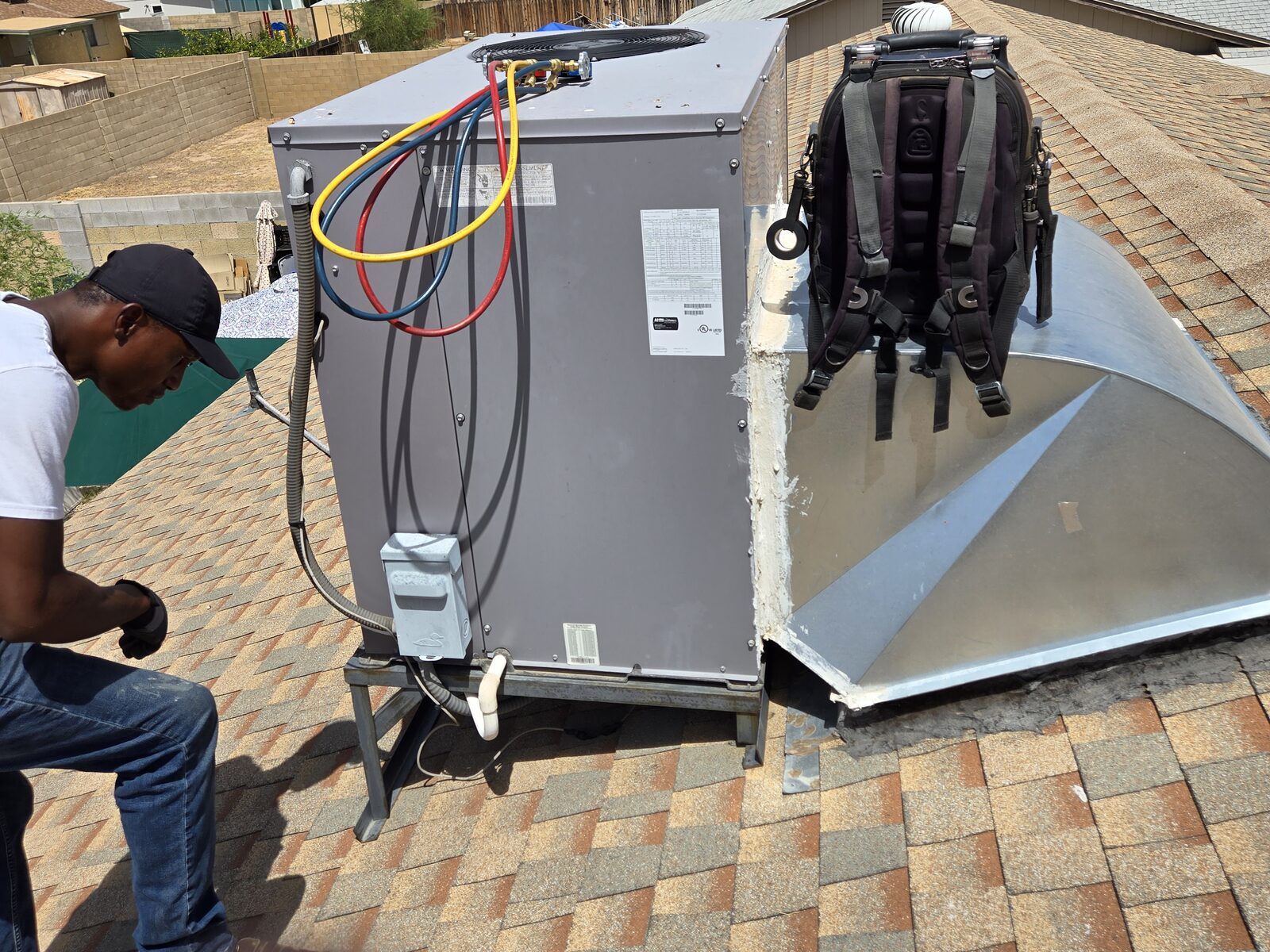 Technician checking rooftop AC system readings during a no-cooling service call
