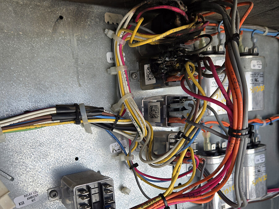 Outdoor AC electrical compartment with capacitors and wiring checked for a hot burning smell