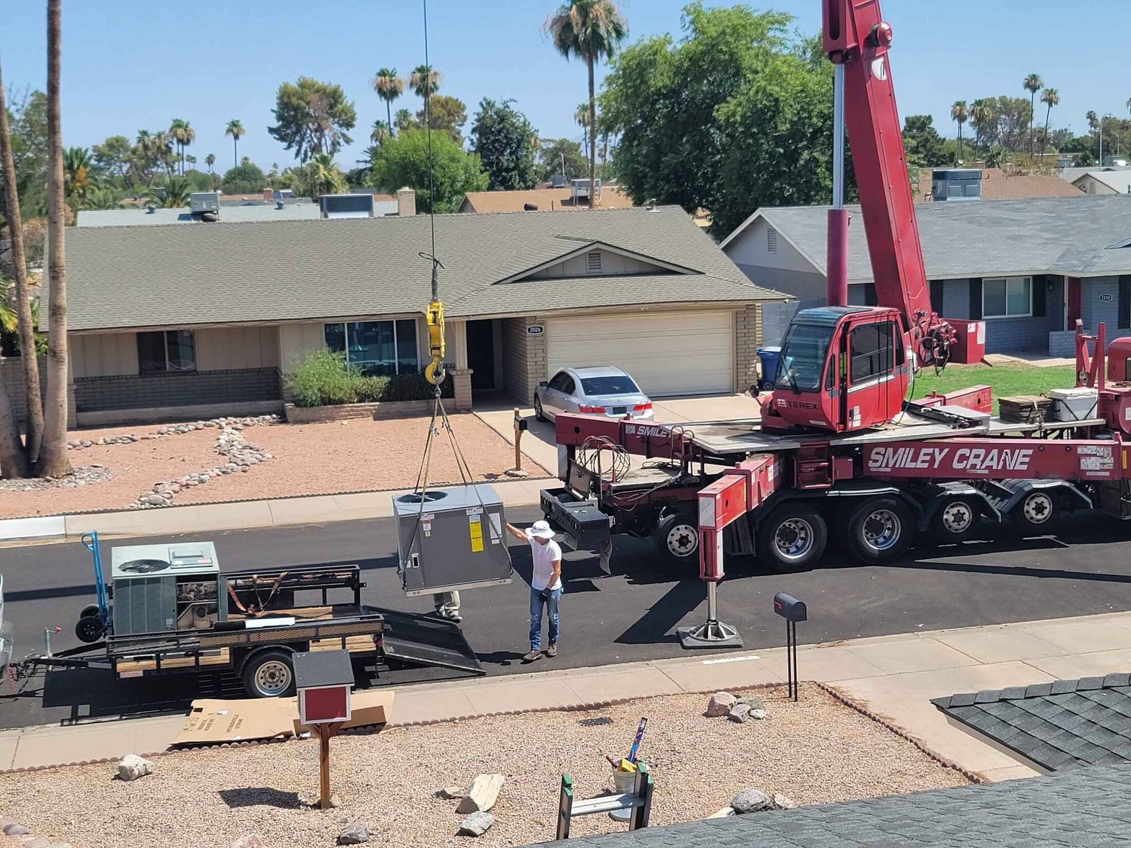 Crane lifting rooftop HVAC equipment during installation