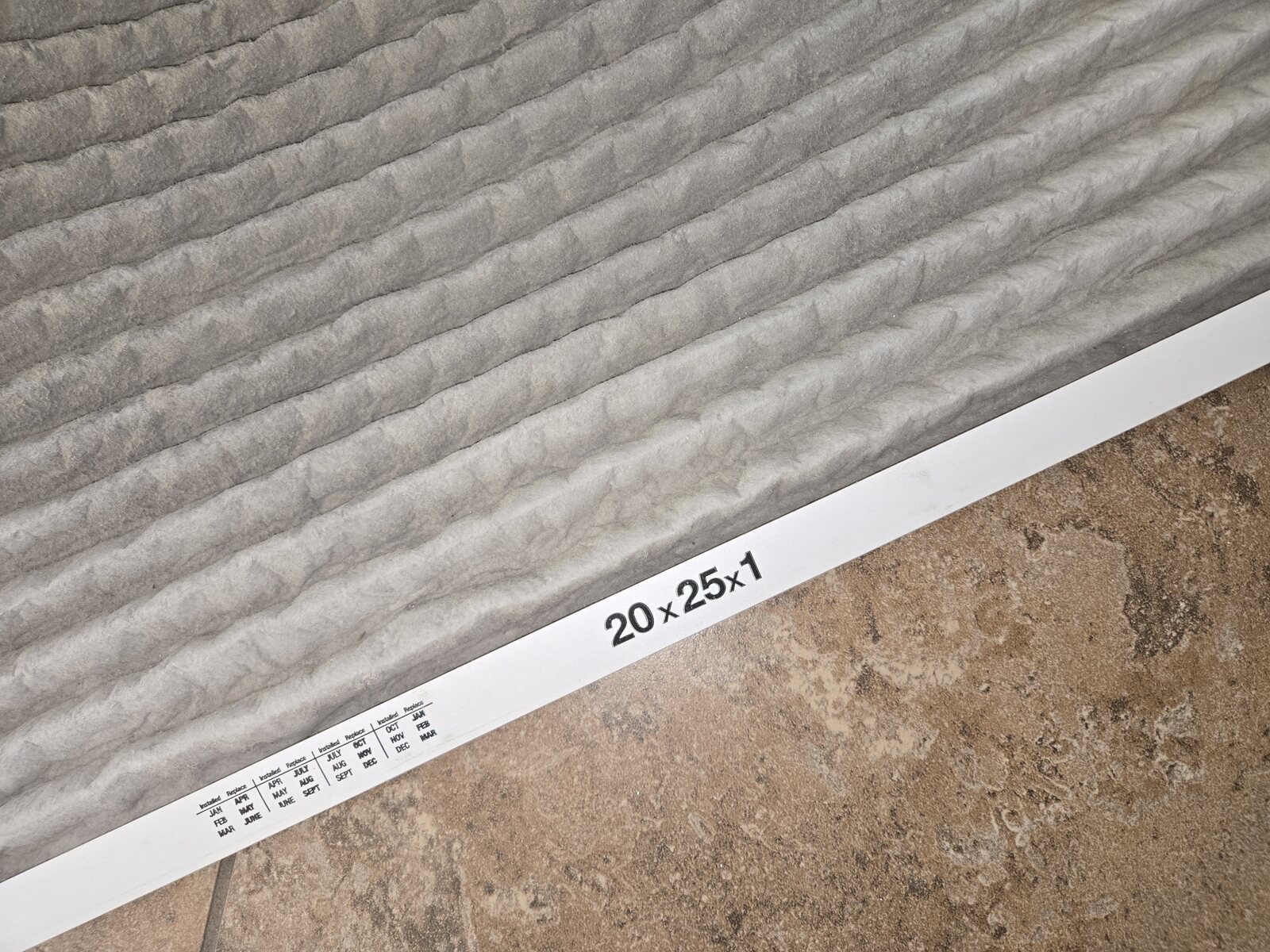 Dirty 20x25x1 HVAC air filter during AC maintenance and airflow check