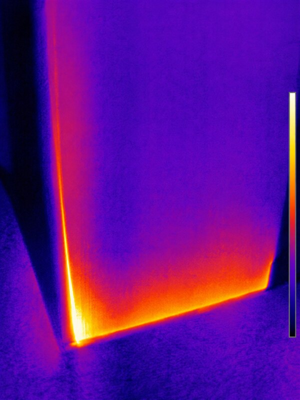 FLIR thermal image showing heat leakage around the bottom and side of a door