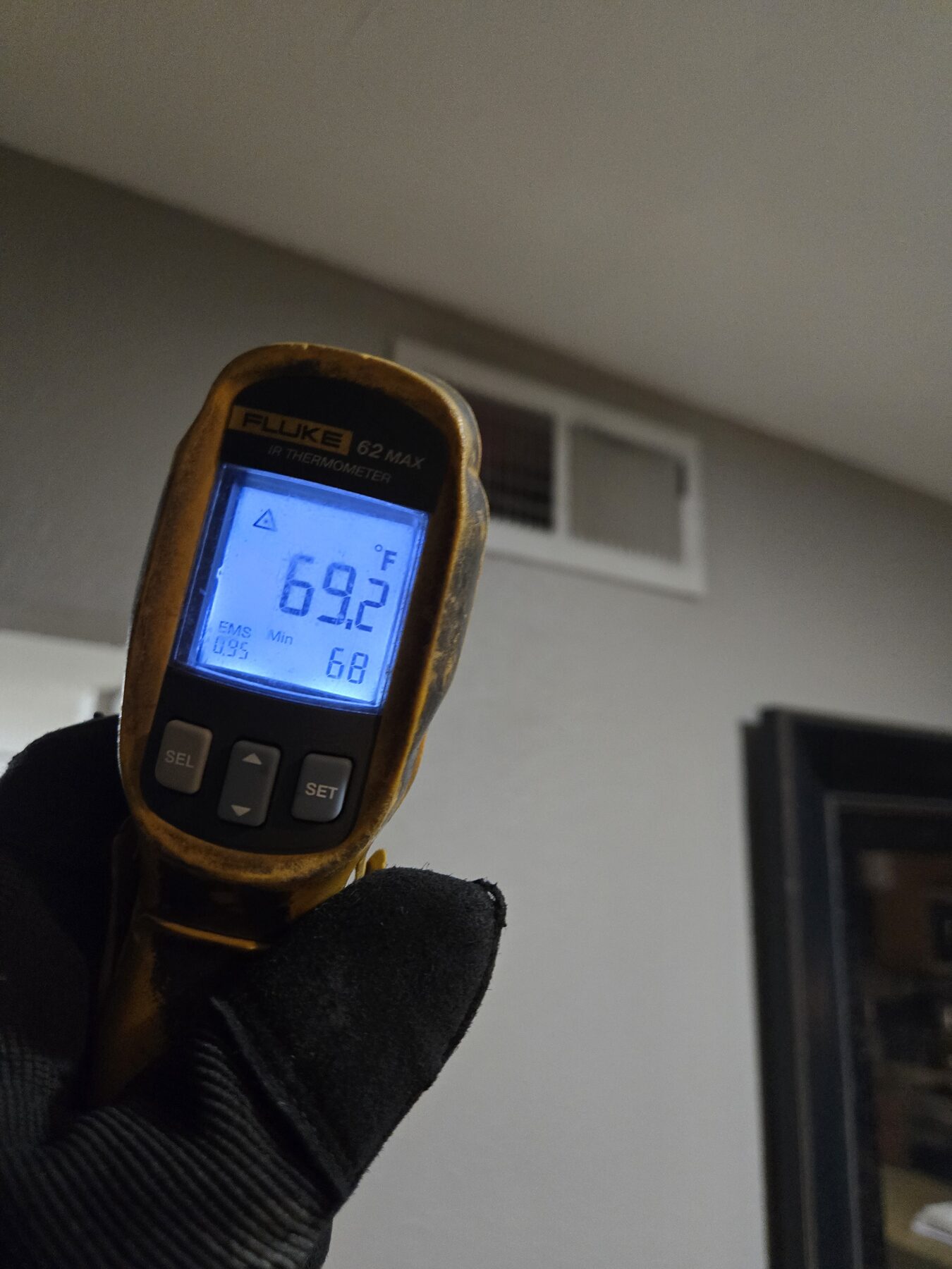 Infrared thermometer showing temperature reading at an air vent