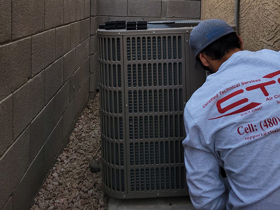Technician performing a heating tune-up on an outdoor HVAC unit in the Phoenix area